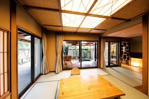 a room with a wooden table and large windows at Yumeguri no Yado Yoshiharu in Izunokuni