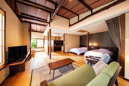 伊豆の国市にある湯めぐりの宿 吉春のベッド2台とソファが備わるホテルルームです。