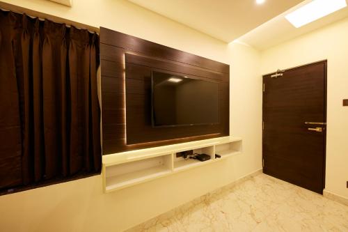 a living room with a television on a wall at Al Noor Palace Business Class Hotel in Chennai