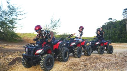 a group of people riding atvs on a dirt road at Pantai Indah Lagoi Bintan in Lagoi