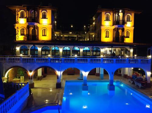 un ponte sopra una piscina di fronte a un edificio di Altinsaray Hotel a Kusadası
