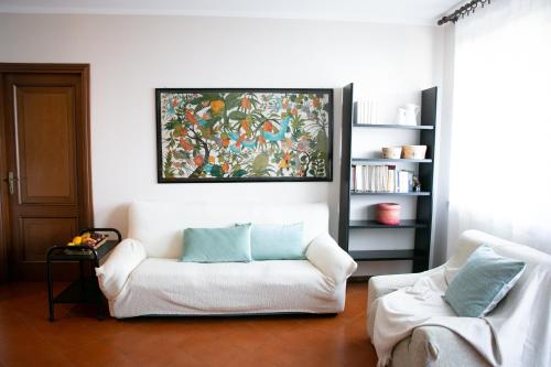 een woonkamer met een witte bank en een schilderij bij IseoLakeRental - Casa Luisa in Riva di Solto