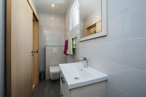a white bathroom with a sink and a toilet at Apartments Mateo in Brela