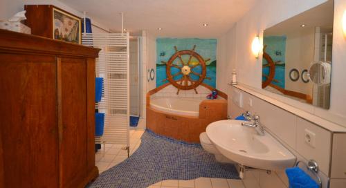 ein Bad mit einer Badewanne, einem Waschbecken und einem Rad an der Wand in der Unterkunft Ferienwohnung Traumschiff in Erzingen