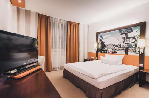 a hotel room with a bed and a flat screen tv at elaya hotel stuttgart ludwigsburg ehemals Abacco by Rilano in Korntal-Münchingen