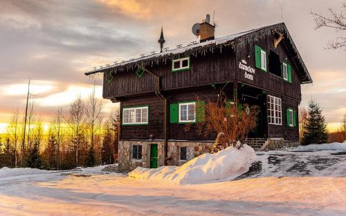 an old wooden house in the snow with snow piled up at Danielov dom in Vysoké Tatry