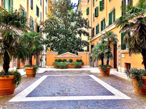 an empty courtyard with palm trees and buildings at La Tana al Flaminio in Rome