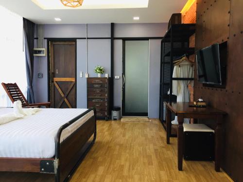 Schlafzimmer mit einem Bett, einem Schreibtisch und einem TV in der Unterkunft Baan Suanfah Kiangdao in Nan