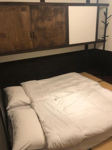 a large white bed in a room with a wooden headboard at Schanze Nozawa in Nozawa Onsen