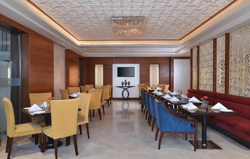 a dining room with tables and chairs and a television at Golden Sarovar Portico in Amritsar