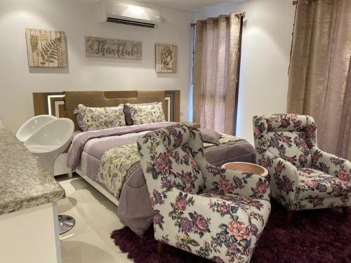 a bedroom with a bed and two chairs at Purple Lily Studio Hawana Lagoons Salalah in Salalah