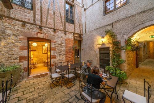 two people sitting at tables in an old building at Hotel Raymond VII in Cordes-sur-Ciel
