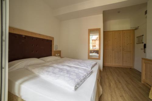 a bedroom with a large white bed and a window at Alpen Hotel Eghel in Folgaria