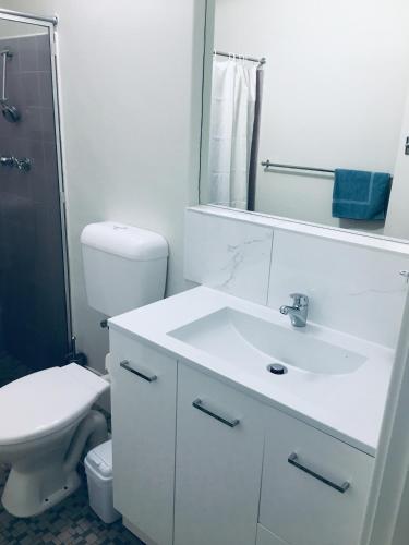 a bathroom with a sink and a toilet and a mirror at The Sands Motel Adelaide in Adelaide