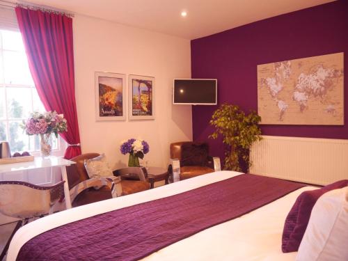 Guestling Hall Hotel في Guestling: غرفة نوم مع سرير والجدران الأرجوانية وطاولة