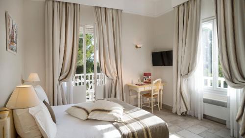 a bedroom with a bed, chair, table and window at Grand Hôtel Les Lecques in Saint-Cyr-sur-Mer