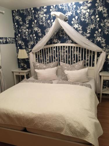 a bedroom with a white bed with blue floral wallpaper at Gästehaus Schmidt in Boltenhagen