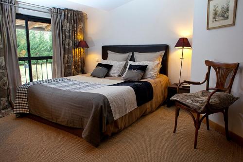 1 dormitorio con 1 cama, 1 silla y 1 ventana en Chambres d'hôtes La Masquière, en Villefranche-de-Lauragais
