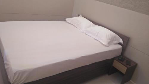Una cama con sábanas blancas y almohadas. en LEMON RESIDENCY By Chungath, en Trichūr