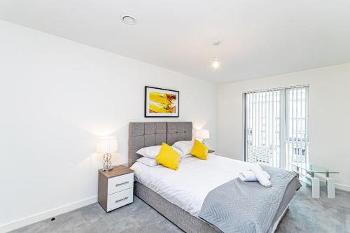 a white bedroom with a bed and a window at Halo House Apartments in Manchester