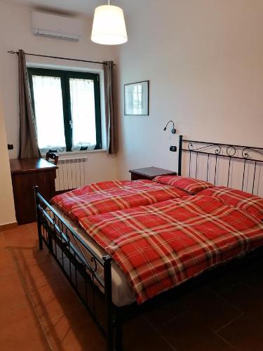 a bedroom with a bed with a red plaid blanket at Le Vecchie Scuderie in Passo Corese