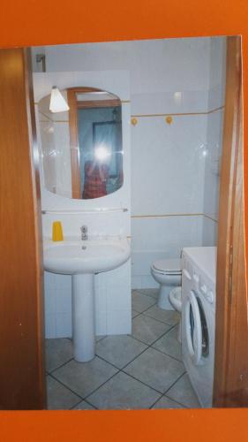 W łazience znajduje się umywalka, toaleta i lustro. w obiekcie LE SALINE w mieście Calasetta
