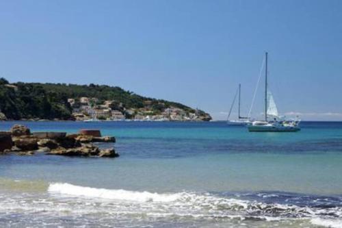 un voilier dans l'océan avec un bateau dans l'eau dans l'établissement Appartement T2 Rez de villa proche bord de mer, au Pradet