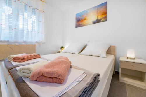 ein Schlafzimmer mit einem weißen Bett mit Handtüchern darauf in der Unterkunft Apartment Lana in Baška