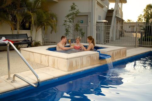 3 personas sentadas en una bañera de hidromasaje en una piscina en Route 66 Motor Inn, en Emerald