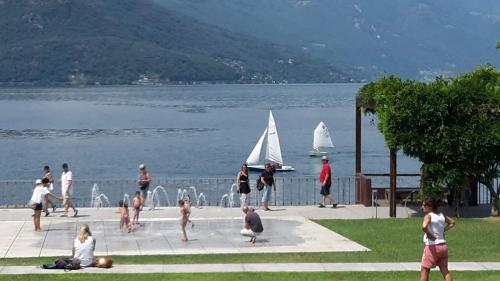 a group of people on a sidewalk near the water with sailboats at Vesna Loft in Luino in Luino