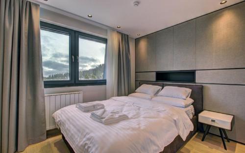 Un dormitorio con una gran cama blanca con ventana. en Alpin Apartments Jahorina, en Jahorina