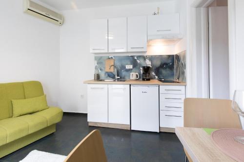 uma cozinha com armários brancos e um sofá verde em Apartment Lauro Opatija, ground floor, parking, near sea em Opatija