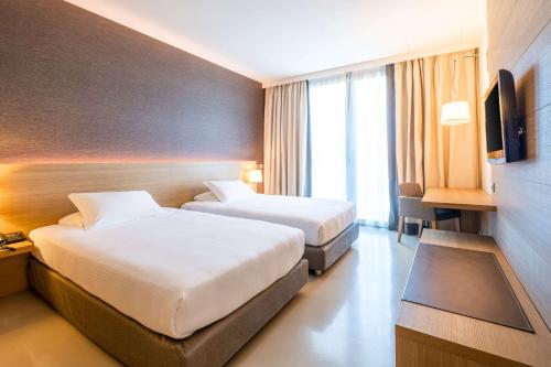 a hotel room with two beds and a television at HSM Hotel San Martino in Garbagnate Monastero 