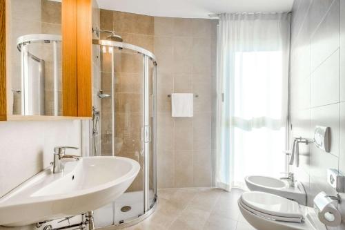 bagno con lavandino, 2 servizi igienici e doccia di Quality Hotel San Martino a Garbagnate Monastero
