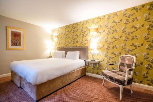 a bedroom with a large bed and a chair at Makeney Hall Hotel in Derby