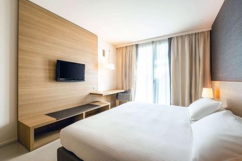 Garbagnate Monastero にあるQuality Hotel San Martinoのベッドとテレビが備わるホテルルームです。
