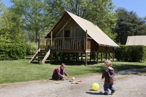 a man and a boy playing with balls in front of a house at Camping le Nid du Parc in Villars-les-Dombes