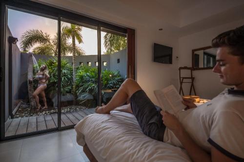 a man sitting on a bed reading a book at La Toubana Hotel & Spa in Sainte-Anne