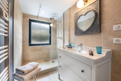 a bathroom with a sink and a mirror and a tub at Le Clos Caroline in Brides-les-Bains