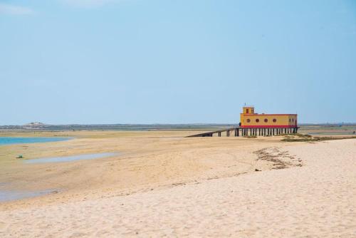 a sandy beach with a lighthouse on a pier at Cozy Fuseta Townhouse with Terrace Roof Solarium, 5min to Beach in Fuzeta