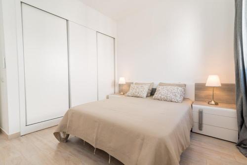 a white bedroom with a large bed with two pillows at Cozy Fuseta Townhouse with Terrace Roof Solarium, 5min to Beach in Fuzeta