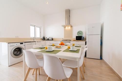a white kitchen with a table and white appliances at Cozy Fuseta Townhouse with Terrace Roof Solarium, 5min to Beach in Fuzeta