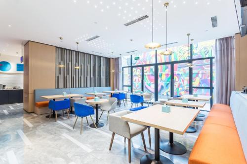 a dining room with tables and blue chairs at Holiday Inn Express Xi'an Ancient Town West by IHG in Xi'an