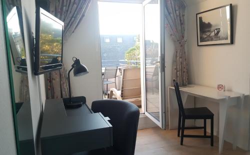 Habitación con escritorio, silla y ventana. en Hotel De L'Europe, en Perros-Guirec