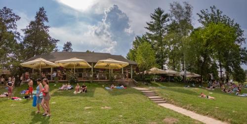 Holiday resort & camping Bela krajina - river Kolpa في متليكا: مجموعة من الناس جالسين على العشب امام مبنى