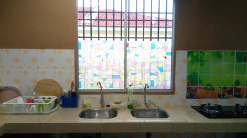 a kitchen counter with two sinks and two windows at RIZQI HOMESTAY Sungai Siput with Wifi! Islamic Guest Only! in Kampong Rimba Panjang
