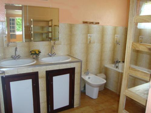 ein Badezimmer mit zwei Waschbecken, einem WC und einem Spiegel in der Unterkunft CASAMELIAS "Le camélia" in Cilaos