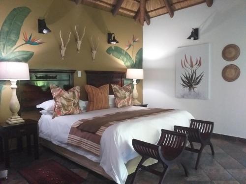a bedroom with a large bed with two chairs at Lodge Afrique in St Lucia