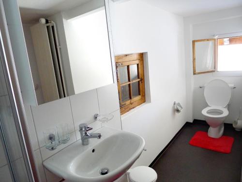 a bathroom with a sink and a toilet and a mirror at Casa Cadruvi, Ferienhaus in Obersaxen, 150 Quadratmeter in Obersaxen
