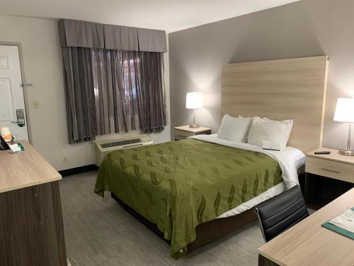 una camera d'albergo con letto e copriletto verde di Quality Inn Airport East a El Paso